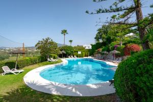 a swimming pool in a yard with a chair and trees at Las Pergolas in Marbella