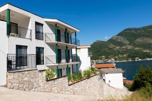 a white building with balconies and a wall at Apartmani Natal in Donja Lastva
