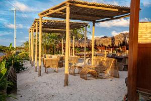 a table and chairs under a pavilion on the beach at AREIA BRANCA Chalés in Santo Amaro