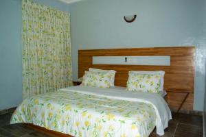 a bedroom with a large bed with a wooden headboard at Hôtel LEWI 1 Bouaké in Bouaké