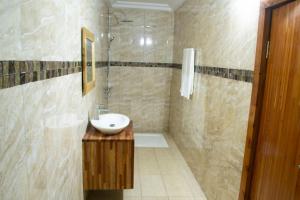 a bathroom with a sink and a shower at Hôtel LEWI 1 Bouaké in Bouaké