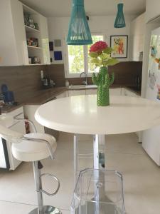 a kitchen with a white table with a vase with flowers at Maison MATIASMA avec Jacuzzi in Hyères +14 photos