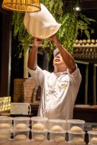 a chef is holding up a pot of food at AREIA BRANCA Chalés in Santo Amaro