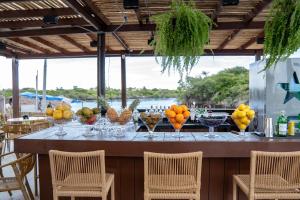 a table with bowls of fruit on it with chairs at AREIA BRANCA Chalés in Santo Amaro