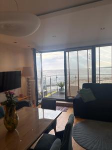 a living room with a table and a view of the ocean at Apartamenty Laguna Przy Latarni in Darlowko