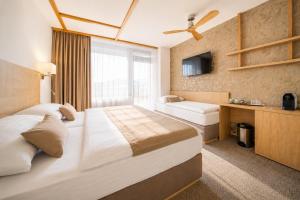 a hotel room with a large bed and a window at Hotel Adamantino in Luhačovice +57 photos