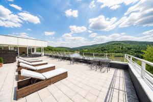 a patio with chairs and tables on a roof at Hotel Adamantino in Luhačovice