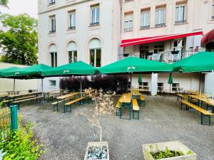 a patio with tables and green umbrellas in front of a building at Hôtel d'Angleterre in Vittel