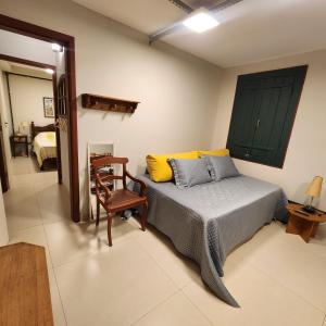 a bedroom with a bed with yellow pillows and a chair at Loft Macau in Diamantina