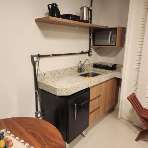 a small kitchen with a sink and a microwave at Loft Macau in Diamantina