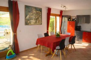 a dining room with a red table and chairs at Résidence les Papaillons in Enney