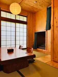 a dining room with a wooden table and a large window at Guest house Mitaki in Hiroshima
