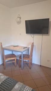 a table with two chairs and a television on a wall at Hostel pod Modrzewiem in Świnoujście