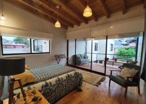 a bedroom with a bed and a couch and windows at Casa Colibri San Cristobal in San Cristóbal de Las Casas