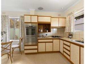 a kitchen with wooden cabinets and a stove top oven at Spacious and Modern Guest House in Gilles Plains