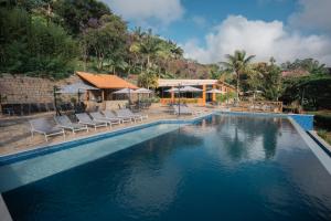 a swimming pool with chairs and a house at Matiz Igaratá Resort, Spa e Eventos in Igaratá