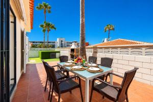 a table and chairs on a patio with palm trees at CHALET 83 con PISCINA PRIVADA in Callao Salvaje