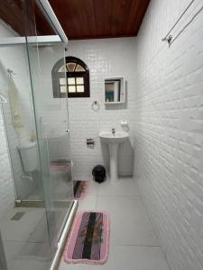 a white bathroom with a shower and a sink at Apartmento102 - Condomínio Brisa Mar in Cabo Frio