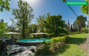 a swimming pool in a yard with umbrellas at Le mas du goïo in Seillans