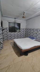 a bed in a room with a tv on a wall at Shree Hariraj Guest House in Vapi