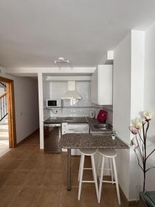 a kitchen with white cabinets and a table with stools at Turquesa Zon & Strand Carihuela in Torremolinos