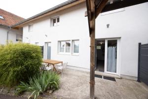 a white house with a wooden table in the courtyard at Triple Evasion Terrasse in Zillisheim