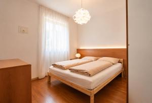 a bedroom with a bed with a chandelier at Appartamento Brione Lido in Nago-Torbole