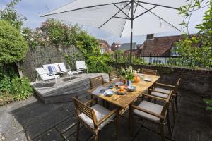 a wooden table with chairs and an umbrella on a patio at Watch Cottage in Lymington