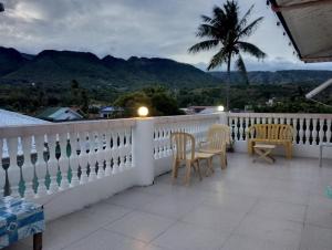 a balcony with a white fence and chairs and a palm tree at The Cronin Residence in Oslob