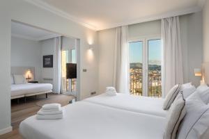 a hotel room with two beds and a large window at Hotel Montjoi by Brava Hoteles in Sant Feliu de Guíxols +34 photos