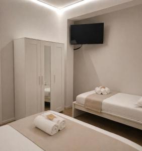 a white room with two beds and a flat screen tv at Mary's Sweet Home in Cagliari
