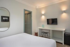 a white bedroom with a bed and a mirror at Hotel Montjoi by Brava Hoteles in Sant Feliu de Guíxols