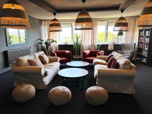 a living room with couches and tables and windows at Hotel New Skanpol in Kołobrzeg