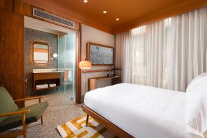 a bedroom with a bed and a chair and a mirror at Hotel 1935- By Adam Hotels in Tel Aviv
