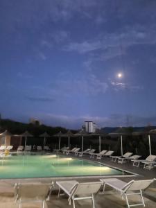 a swimming pool with chairs and the moon in the sky at Hotel "SAN SAENA " in Vlorë