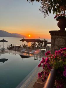 a pool with the sun setting over the water at Hotel "SAN SAENA " in Vlorë