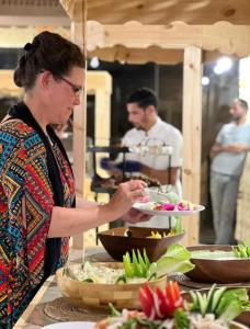 a woman holding a plate of food at a buffet at WADI RUM REGENCY BUBBLE lUXURY in Wadi Rum