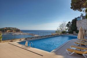 a swimming pool with chairs and an ocean view at Hotel Montjoi by Brava Hoteles in Sant Feliu de Guíxols
