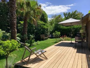 a wooden deck with a chair and an umbrella at La Crampotte de Bidart, proche Océan in Bidart