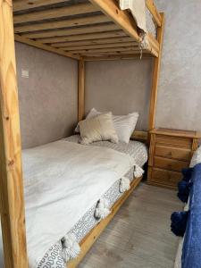 a wooden bunk bed with white sheets and pillows at Abrid Surf in Tamraght Ouzdar