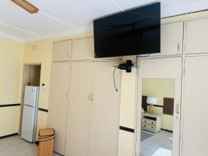 a flat screen tv on a wall in a living room at Garden Nest Guest House in Vanderbijlpark