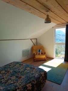 a bedroom with a bed and a chair and a window at Chez JF et ISA in Bussang