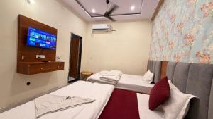 a room with two beds and a tv on the wall at Shri Hit Maya Dham in Vrindāvan