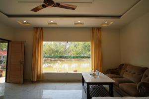 a living room with a couch and a large window at Lake View Village Resort in Tajpur