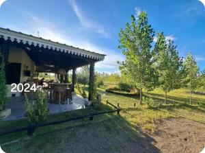 a farmhouse with a patio and trees in a field at El Madejo - del Valle de Uco in Tunuyán