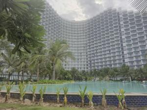 a large building with a pool in front of it at Arena Lucky Condotel in Cam Ranh International Airport