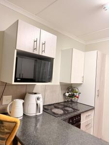 a kitchen with white cabinets and a stove and a microwave at Kilimanjaro in Alberton