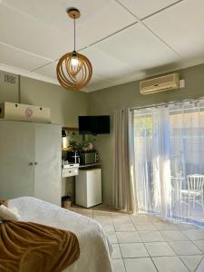 a bedroom with a bed and a kitchen with a window at Guesthouse 52 in Groblersdal