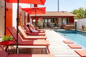 a group of chairs and umbrellas next to a pool at Hôtel Villa Maïtia in Ustaritz