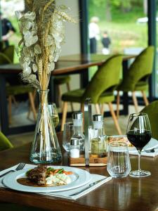 a table with a plate of food and a vase of flowers at Hotel Băile Bughea in Bughea de Sus +16 photos